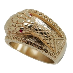 May include: A gold ring with a detailed snake design. The snake's head is raised and has red eyes. The ring is decorated with a pattern of circles and a triangle.