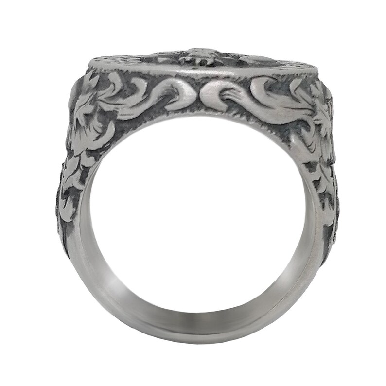 K&ouml;nnte beinhalten: Ein silberner Ring mit einem komplizierten Design, das ein florales Motiv und ein zentrales Design aufweist. Der Ring ist aus Metall und hat eine polierte Oberfl&auml;che.