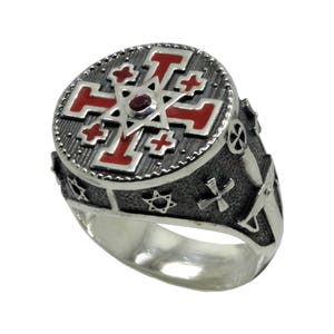 May include: A silver ring with a red enamel cross and star of David design. The ring is decorated with other religious symbols.