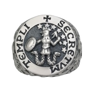 K&ouml;nnte beinhalten: Ein silberner Ring mit einem schwarz-wei&szlig;en Design. Der Ring zeigt eine Figur mit einem Schild und einer Schlange, umgeben von den Worten "TEMPLI SECRETVM".