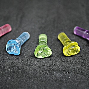 May include: Five small plastic rose-shaped ornaments in different colors: pink, blue, green, yellow, and purple.