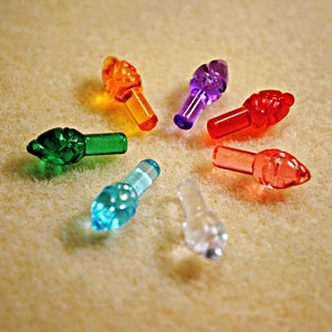 May include: Assortment of colorful Christmas light bulbs in various shapes, including a green leaf, a blue star, a clear teardrop, and a red and orange teardrop.