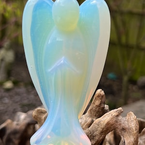 Könnte beinhalten: Eine weiße Opal-Engelfigur mit transluzenter, irisierender Oberfläche. Der Engel steht mit gefalteten Händen im Gebet.