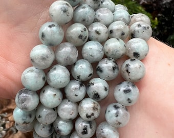 May include: A bracelet made of round, white and black speckled beads. The beads are about 1 cm in diameter.