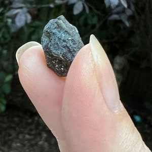 May include: A small, dark grey, irregularly shaped rock with a rough, textured surface.