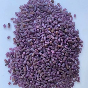 May include: A large pile of small, purple, rough, and pointed ruby crystals.