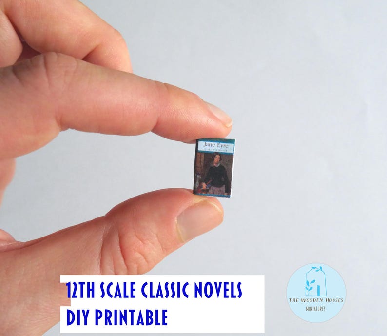 May include: A tiny book titled "Jane Eyre" with a blue cover, held between fingers. The book features a person on the cover. Text at the bottom reads "12th Scale Classic Novels DIY Printable". A logo for "The Wooden Houses Miniatures" is also visible.