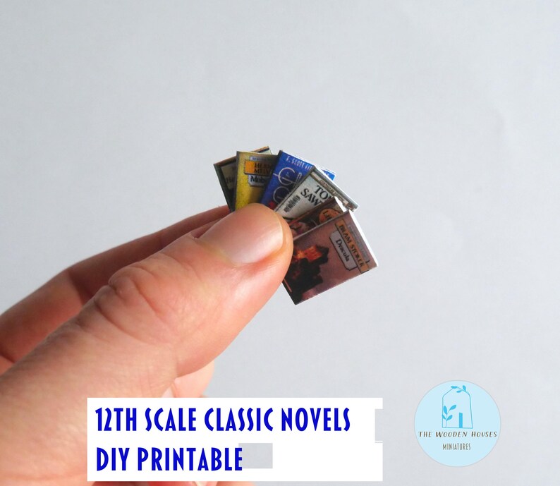 May include: A hand holding a small stack of miniature classic novels. The book covers are visible, with titles including "Tom Sawyer" and "MAM SIROKER Descule". The text "12TH SCALE CLASSIC NOVELS DIY PRINTABLE" is at the bottom.