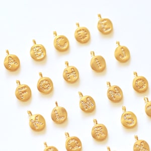 Puede incluir: Un conjunto de 26 abalorios dorados, cada uno con una letra diferente del alfabeto, adornados con pequeñas piedras brillantes. Los abalorios son perfectos para añadir un toque personalizado a las joyas.