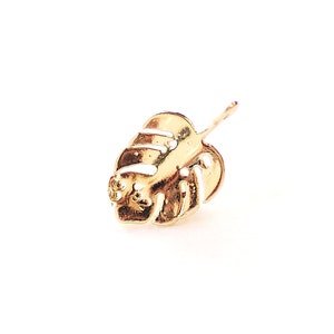May include: A gold-colored earring featuring a detailed monstera leaf design.