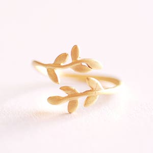 May include: A gold-toned ring with a delicate design of two intertwined branches with leaves.