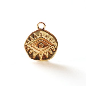 Puede incluir: Encanto dorado con un dise&ntilde;o de ojo detallado, rodeado de un patr&oacute;n de estrella. El encanto es un s&iacute;mbolo popular de protecci&oacute;n y buena suerte.