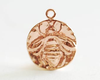 May include: A gold-toned pendant featuring a detailed bee design. The pendant is round and has a smooth, polished finish.