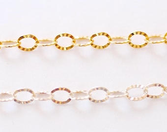May include: Two chains, one gold and one silver, with oval links. The links have a textured, ridged design.