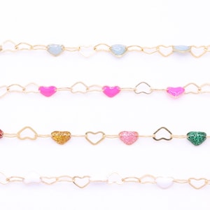 May include: Four strands of decorative chain with heart-shaped links and colorful heart-shaped beads. The chains feature gold-colored metal links and beads in shades of blue, pink, red, gold, and white. The background is plain white.