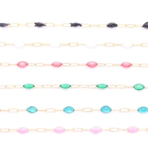 Puede incluir: Primer plano de varios collares delicados con cadenas de oro y cuentas de piedras preciosas de colores. Las cuentas son de varios colores, incluyendo negro, blanco, rosa, verde, azul y rosa claro. Los collares se muestran sobre un fondo blanco.