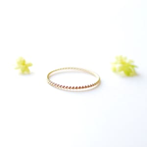 May include: A thin gold band ring with a twisted design.
