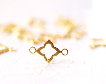 Pode incluir: Conector de metal dourado com um design de trevo de quatro folhas e dois laços redondos. O conector é projetado para a fabricação de joias.