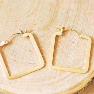 May include: A pair of gold square hoop earrings. The earrings are simple and elegant, and would make a great addition to any jewellery collection.
