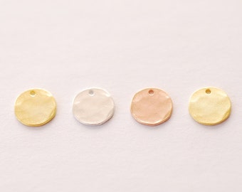 Puede incluir: Cuatro dijes redondos de metal en diferentes colores: oro, plata, oro rosa y latón. Cada dije tiene un pequeño agujero en la parte superior para sujetarlo a un collar o pulsera.