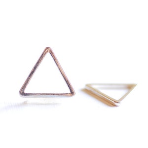 May include: A pair of silver triangle earrings. The earrings are simple and modern in design.