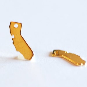 May include: Two gold-colored California state outline charms. The charms are small and delicate, perfect for jewelry making.