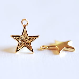 May include: Two gold star-shaped charms with a loop at the top for attaching to jewelry or other crafts.