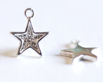May include: Two silver star-shaped charms with a loop at the top. The charm on the left has a textured surface, while the charm on the right is smooth.
