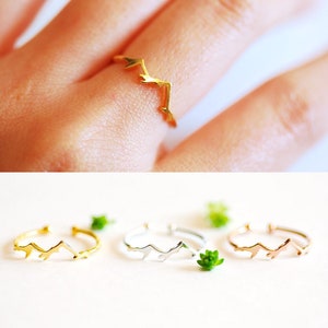 May include: Three gold, silver, and rose gold mountain range rings. The rings are delicate and minimalist.