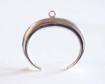 May include: A silver crescent moon pendant charm with a loop at the top for attaching to a necklace or bracelet.
