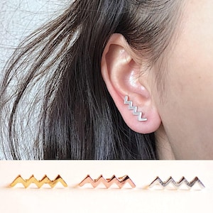 May include: Three ear cuffs in different colors: gold, rose gold, and silver. Each cuff features a zig-zag design.