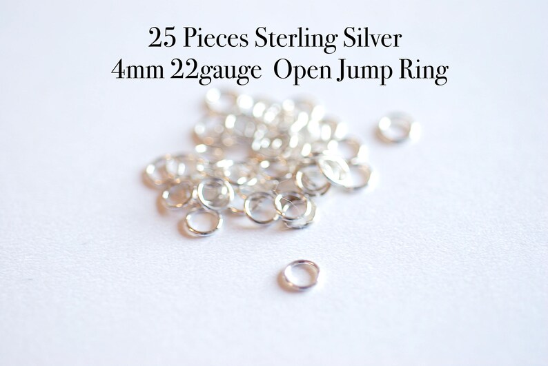 May include: A pile of 25 silver 4mm open jump rings, 22 gauge, on a white surface. 25 Pieces Sterling Silver 4mm 22gauge Open Jump Ring