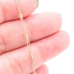 May include: A gold chain necklace with a delicate, oval-shaped link design.