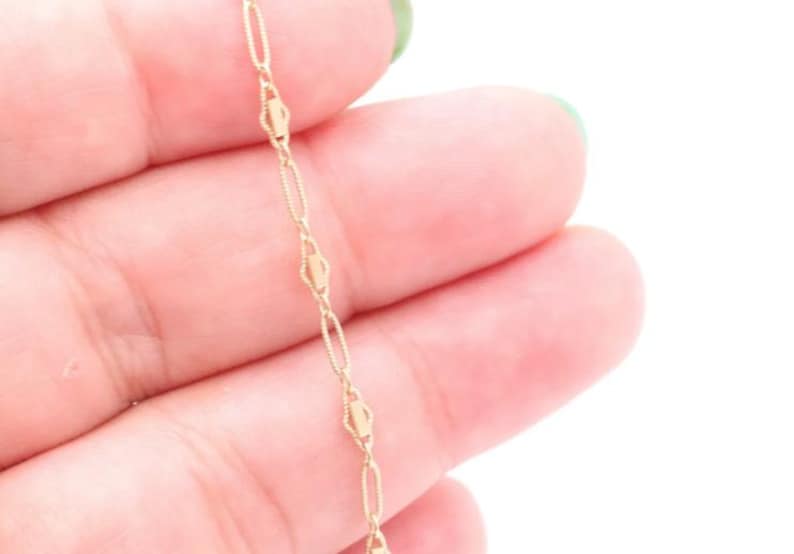 May include: A gold chain necklace with a delicate, oval-shaped link design.