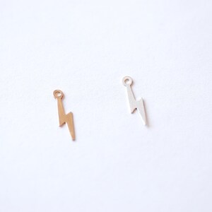 May include: Two lightning bolt charms, one gold and one silver, with a small loop at the top for attaching to jewelry.