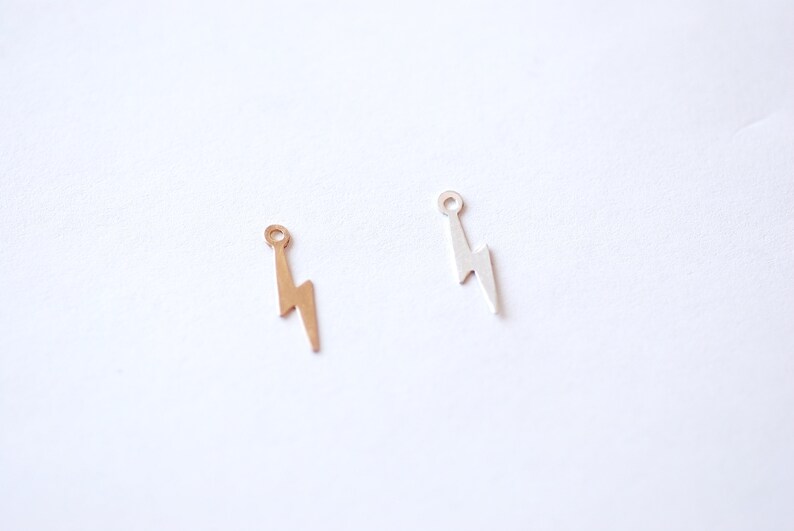 May include: Two lightning bolt charms, one gold and one silver, with a small loop at the top for attaching to jewelry.
