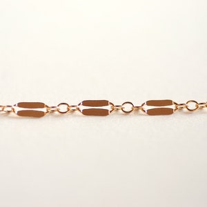 May include: A gold chain necklace with a delicate, rectangular link design.