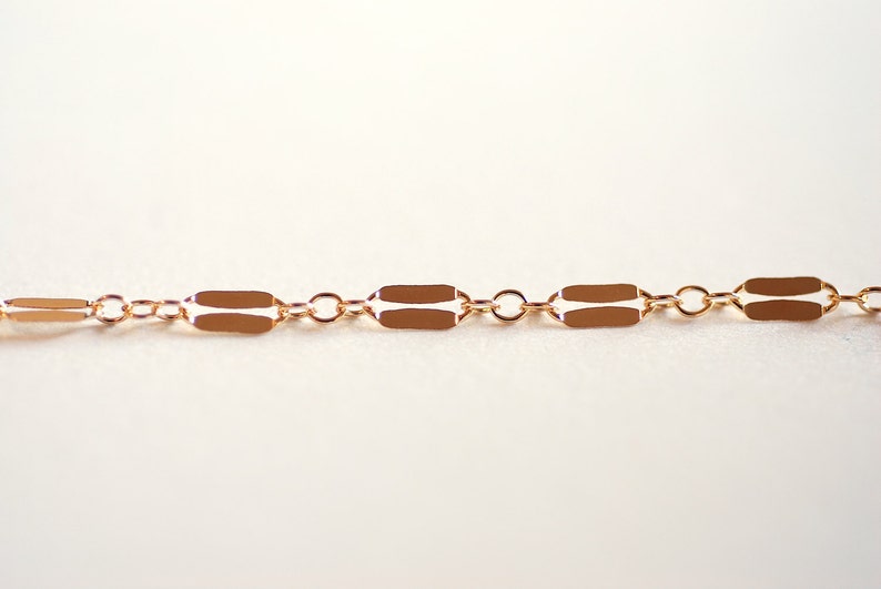 May include: A gold chain necklace with a delicate, rectangular link design.
