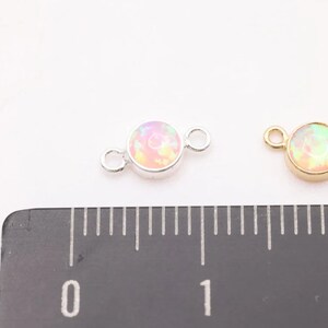 May include: Two round opal connector charms, one silver and one gold, with a 1 cm diameter. The charms have two jump rings for attaching to jewelry.
