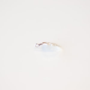 May include: A silver charm in the shape of a leaf with a small loop at the top.