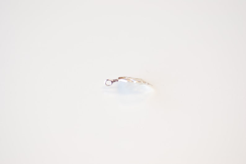 May include: A silver charm in the shape of a leaf with a small loop at the top.