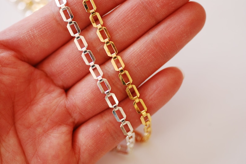 May include: Two chain necklaces, one silver and one gold, with a box chain pattern.