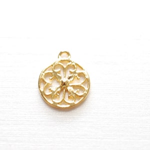 May include: Gold-toned metal pendant with a circular, openwork design featuring a floral pattern.
