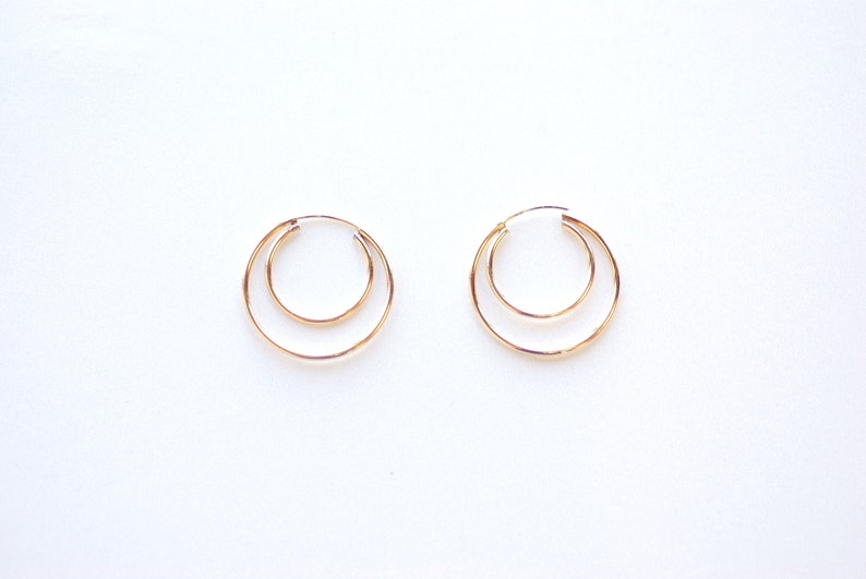 May include: A pair of gold hoop earrings with a double circle design.