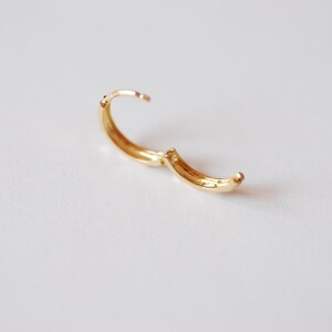 May include: A gold hoop earring with a hinged clasp.