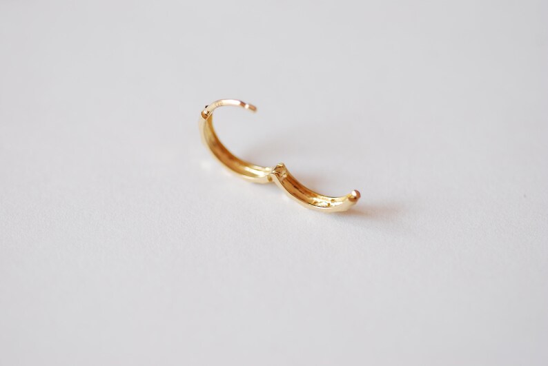 May include: A gold hoop earring with a hinged clasp.