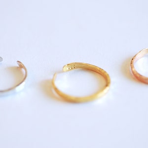 May include: Three hammered metal rings in silver, gold, and rose gold.