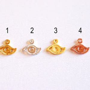 May include: Four gold-toned evil eye charms with a hole at the top for hanging. The charms are numbered 1 through 4.