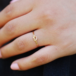 May include: A gold ring with a knot design in the shape of a heart.