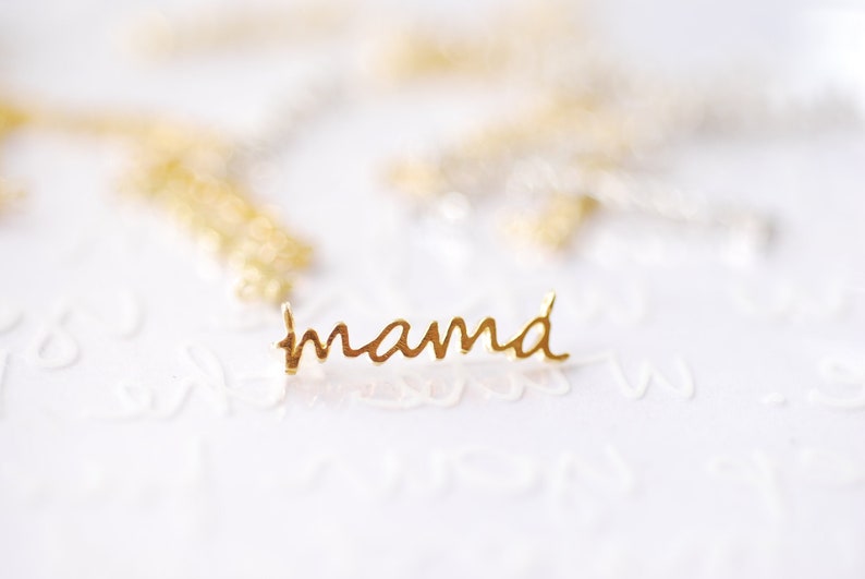 May include: Gold-colored metal pendant with the word "mama" written in cursive.